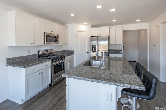 kitchen with appliances with stainless steel finishes, a breakfast bar, dark wood-type flooring, sink, and white cabinetry