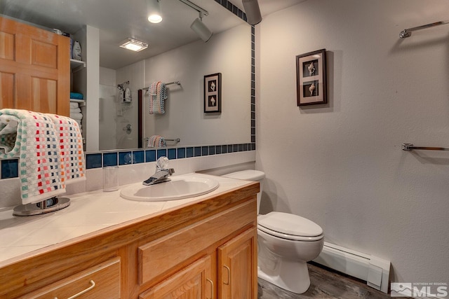 bathroom featuring baseboard heating, toilet, vanity, hardwood / wood-style floors, and tiled shower