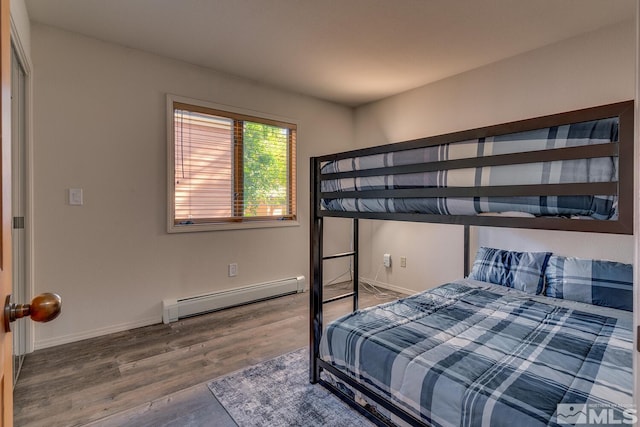 bedroom with a baseboard heating unit and wood-type flooring