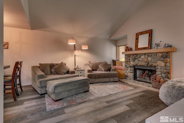 living room featuring high vaulted ceiling, hardwood / wood-style floors, and a stone fireplace