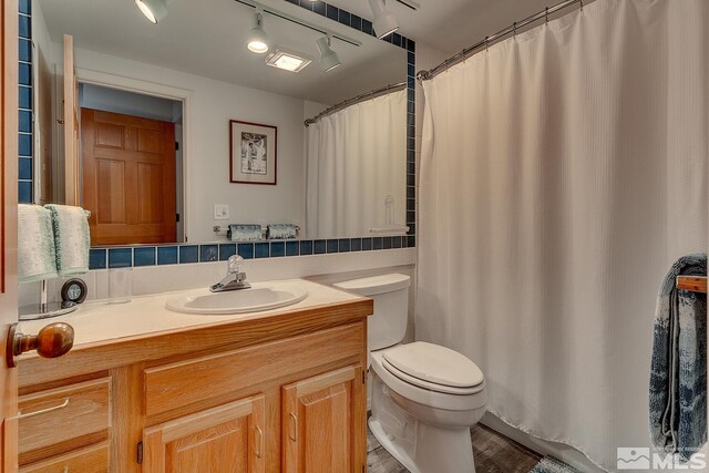 bathroom featuring hardwood / wood-style floors, tasteful backsplash, toilet, and vanity