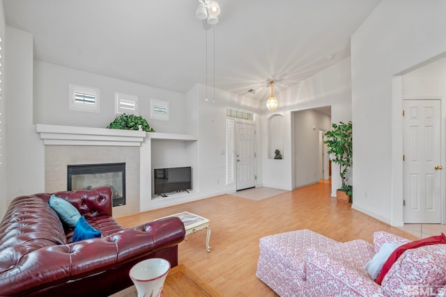 living area with visible vents, baseboards, a tiled fireplace, and wood finished floors