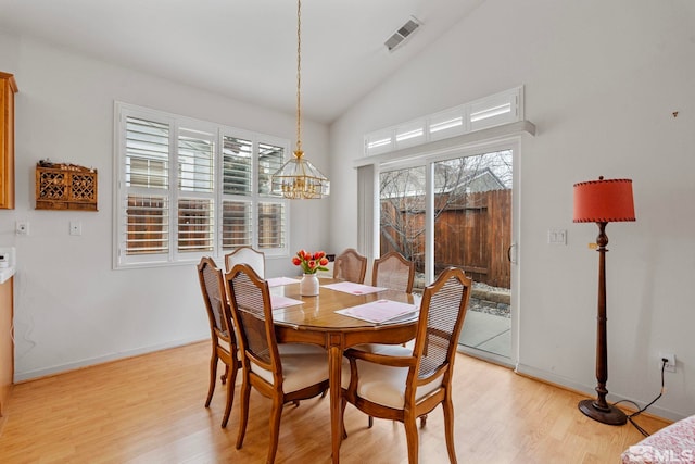 dining room featuring lofted ceiling, light wood-type flooring, visible vents, and baseboards