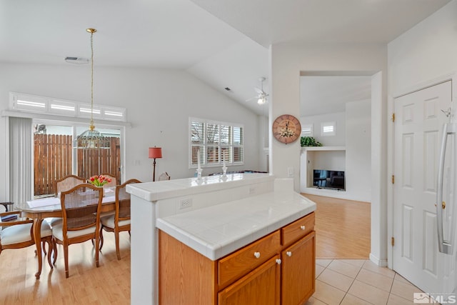 kitchen with a ceiling fan, tile countertops, hanging light fixtures, vaulted ceiling, and light tile patterned flooring