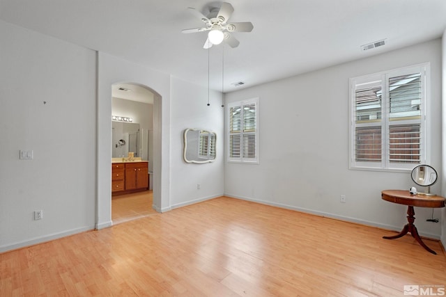 unfurnished room featuring arched walkways, visible vents, and light wood-style flooring