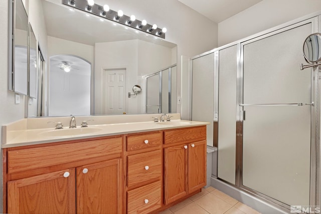 bathroom with a shower stall, double vanity, a sink, and tile patterned floors