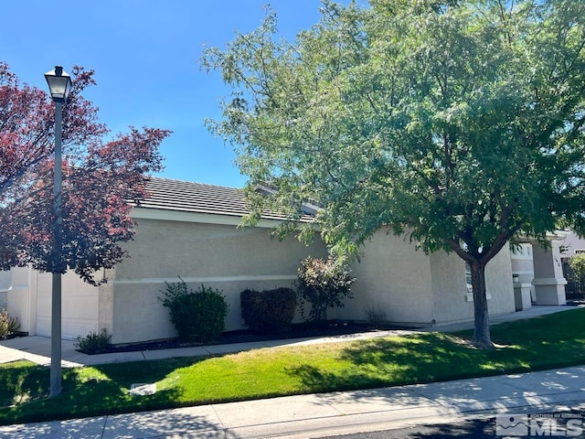 view of property exterior with a garage and a lawn