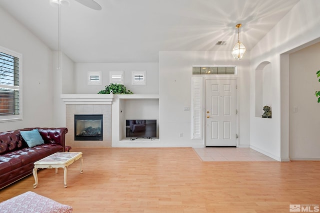 living area featuring a fireplace, visible vents, arched walkways, and wood finished floors