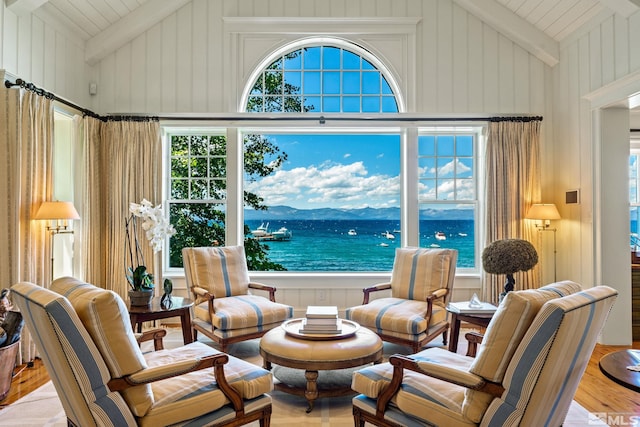 living room featuring a water and mountain view, high vaulted ceiling, beamed ceiling, and light hardwood / wood-style flooring