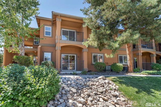 view of front of property featuring a front lawn, central AC unit, and a balcony