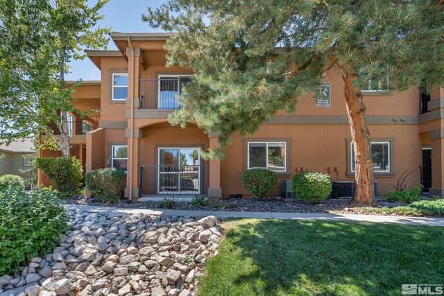 view of front of home with a balcony, central air condition unit, and a front lawn