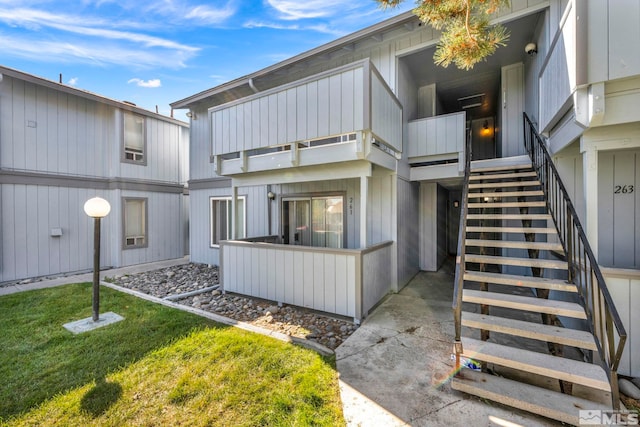 back of property featuring a balcony and a lawn