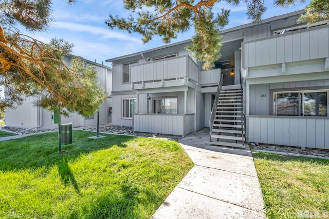 view of front of property featuring a front yard, stairway, and a balcony