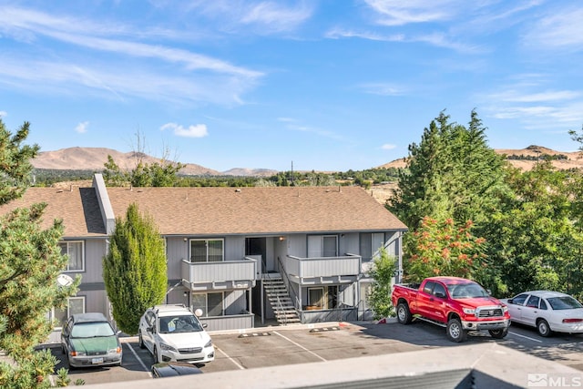 view of front of house with a balcony, stairs, a mountain view, and uncovered parking