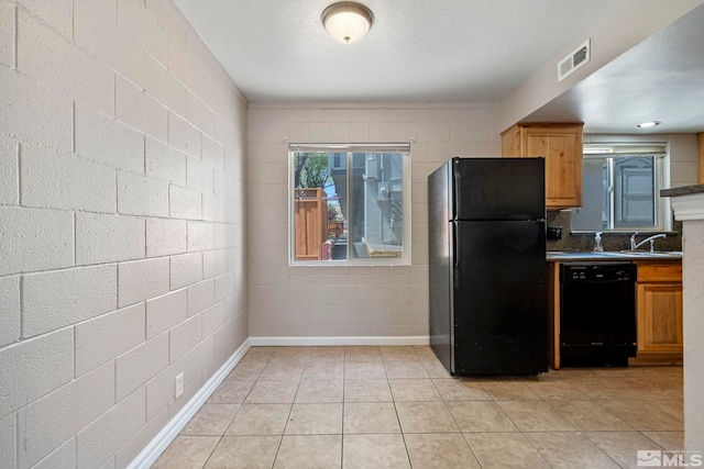 kitchen featuring visible vents, brown cabinetry, dark countertops, black appliances, and a sink