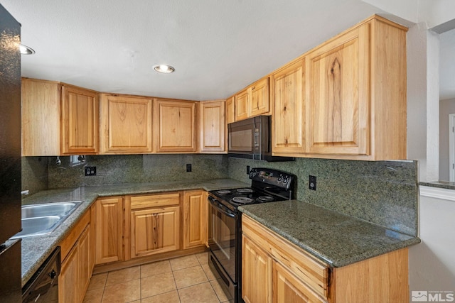 kitchen featuring light tile patterned floors, backsplash, a sink, dark stone counters, and black appliances