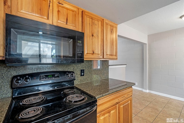 kitchen with light tile patterned floors, tasteful backsplash, baseboards, dark stone countertops, and black appliances