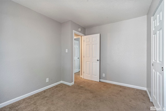 unfurnished bedroom featuring a textured ceiling, baseboards, and carpet flooring