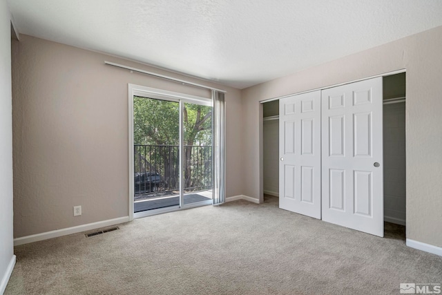 unfurnished bedroom featuring baseboards, visible vents, access to outside, a textured ceiling, and carpet floors