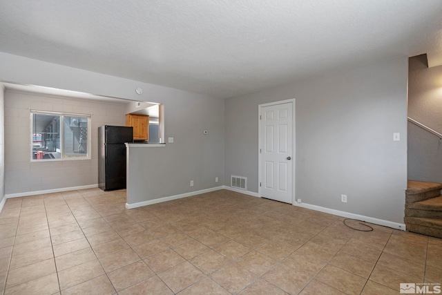 unfurnished living room featuring visible vents, stairway, light tile patterned flooring, a textured ceiling, and baseboards