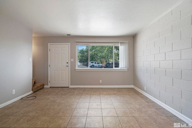 spare room with visible vents, a textured ceiling, baseboards, and light tile patterned floors