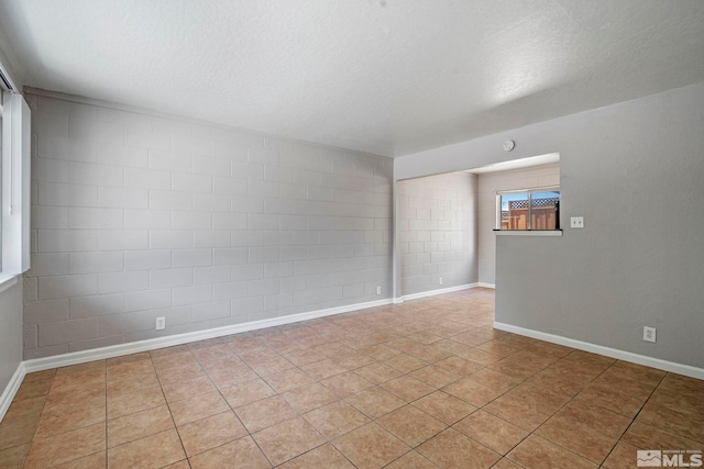 spare room with baseboards, a textured ceiling, and light tile patterned flooring