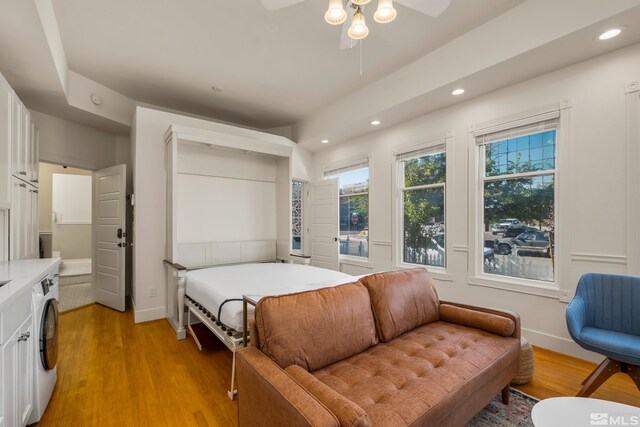 bedroom featuring ceiling fan, light hardwood / wood-style flooring, and washer / dryer