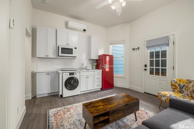 living room with dark hardwood / wood-style floors, sink, washer / clothes dryer, an AC wall unit, and ceiling fan