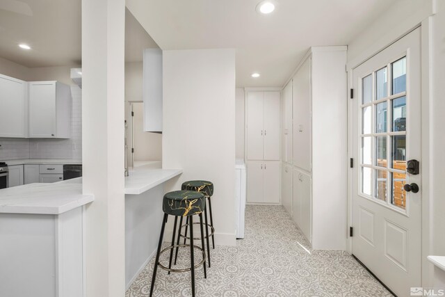 kitchen featuring white cabinets, light tile patterned floors, and tasteful backsplash