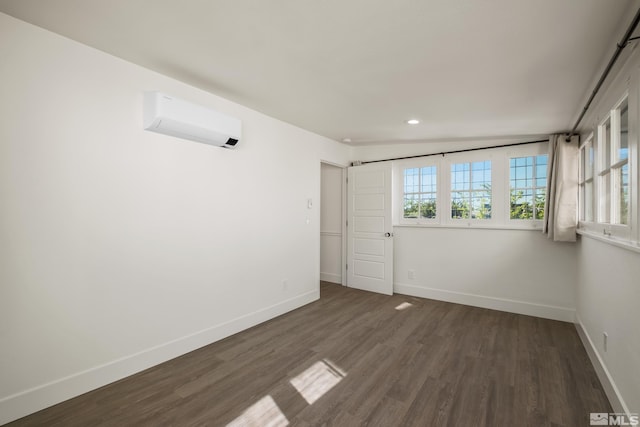 empty room featuring recessed lighting, a wall unit AC, dark wood finished floors, and baseboards