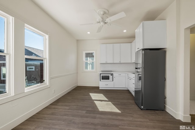 kitchen with light countertops, white microwave, freestanding refrigerator, and white cabinets