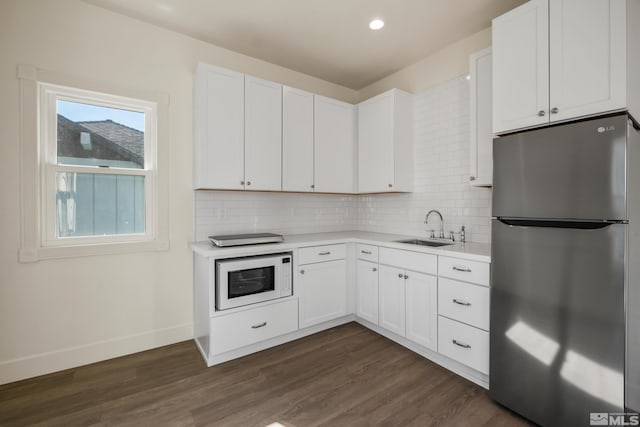 kitchen with freestanding refrigerator, light countertops, a sink, and white microwave