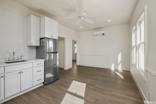 kitchen with sink, dark wood-type flooring, decorative backsplash, stainless steel refrigerator, and white cabinets