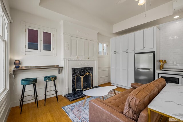 living room with light wood-type flooring, a high end fireplace, and a healthy amount of sunlight