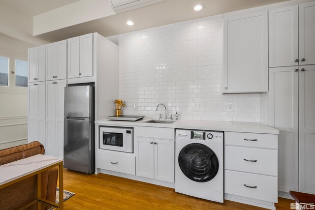 kitchen featuring stainless steel fridge, white microwave, washer / dryer, and light wood-type flooring