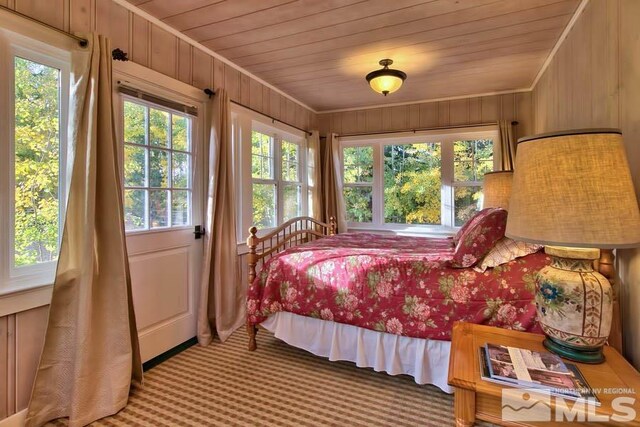 carpeted bedroom featuring wood walls and wooden ceiling