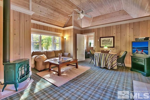 living room featuring a wood stove, wooden walls, lofted ceiling, ceiling fan, and wooden ceiling