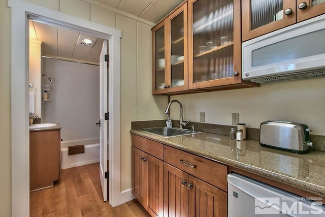 kitchen with sink, dark stone countertops, and light hardwood / wood-style floors