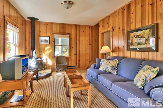 carpeted living room featuring wood walls, baseboard heating, and a wood stove