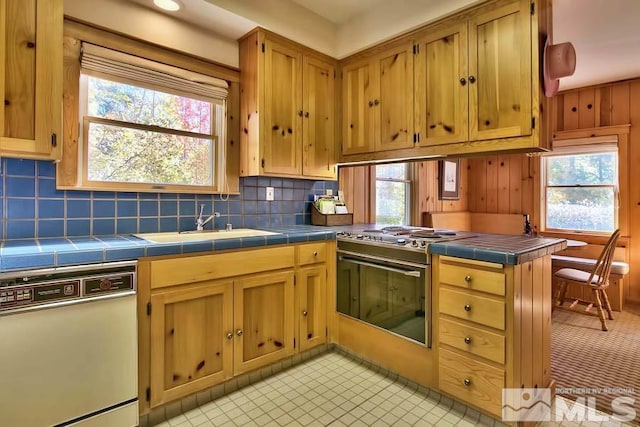 kitchen with tasteful backsplash, sink, light tile patterned floors, tile counters, and white appliances