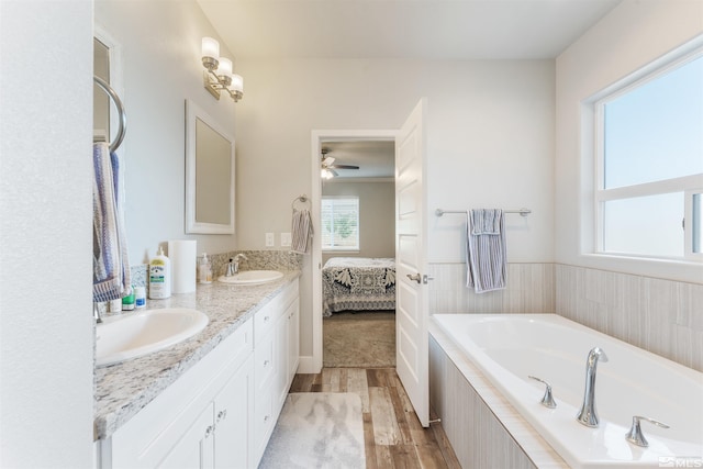 ensuite bathroom featuring plenty of natural light, a sink, and wood finished floors