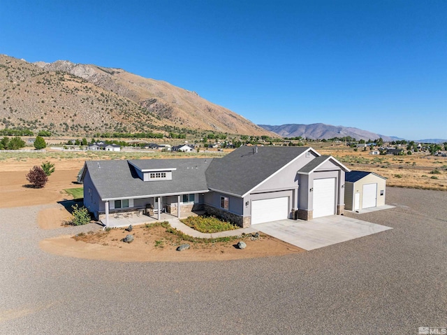 view of front of house with a mountain view, covered porch, a garage, concrete driveway, and stone siding