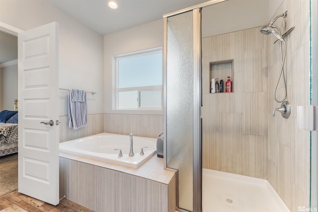 ensuite bathroom featuring a garden tub, a shower stall, connected bathroom, and wood finished floors