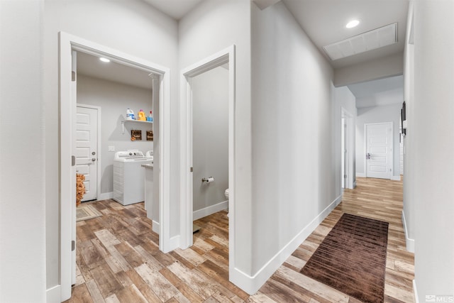 hall featuring light wood finished floors, baseboards, visible vents, washing machine and clothes dryer, and recessed lighting