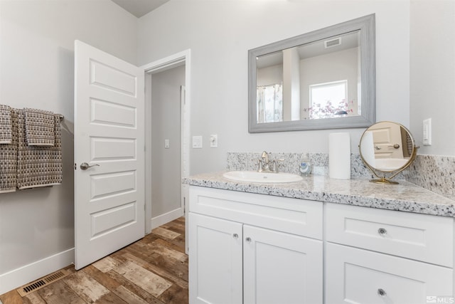 full bathroom featuring vanity, wood finished floors, visible vents, and baseboards