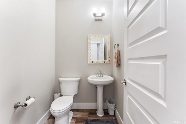 half bathroom with toilet, baseboards, and wood finished floors