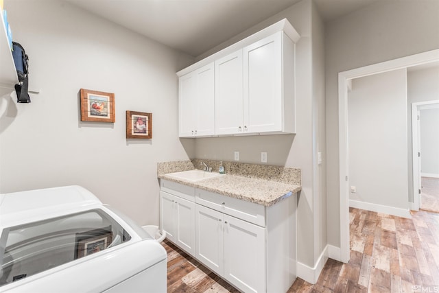 laundry room featuring washer / clothes dryer, a sink, baseboards, cabinet space, and light wood finished floors