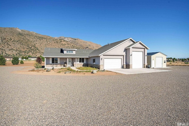 view of front facade featuring driveway, stone siding, an attached garage, covered porch, and a mountain view