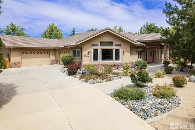 single story home with a garage, a tile roof, stone siding, driveway, and stucco siding