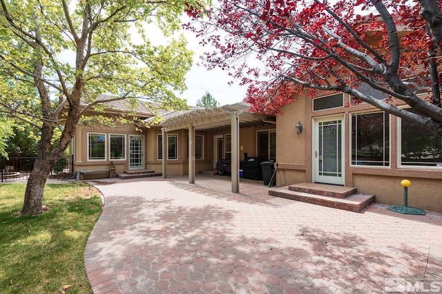 back of property featuring entry steps, a patio area, stucco siding, and a pergola